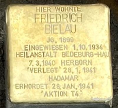 Quadratischer Stolperstein aus Messing gewidmet Friedrich Bielau mit der Gravur: Hier wohnte Friedrich Bielau, JG. 1899, Eingewiesen 1.10.1934 Heilanstalt Bedeburg-Hau, 7.3.1940 Herborn, 'Verlegt' 28.1.1941 Hadamar, Ermordet 28. Jan. 1941 'Aktion T4'