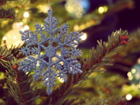 Silbernerner Weihnachtsbaumanhänger Schneeflocke mit Glitzer vor Tannenzweigen